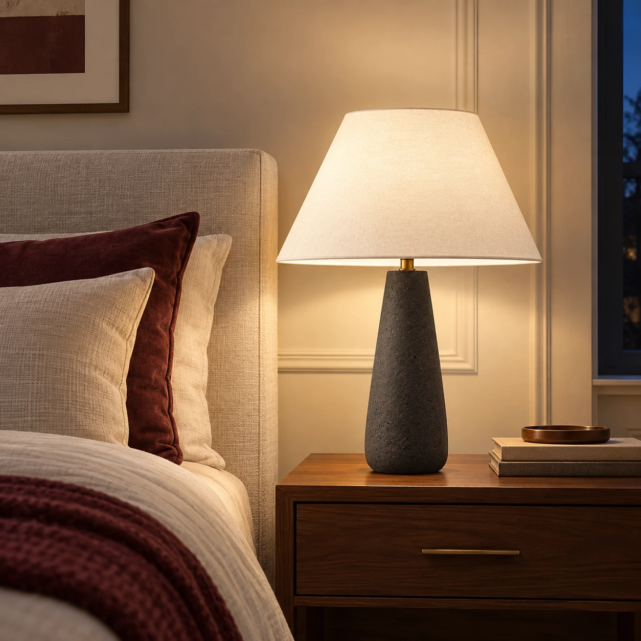 Alden matte black concrete-base lamp glowing beside a bed